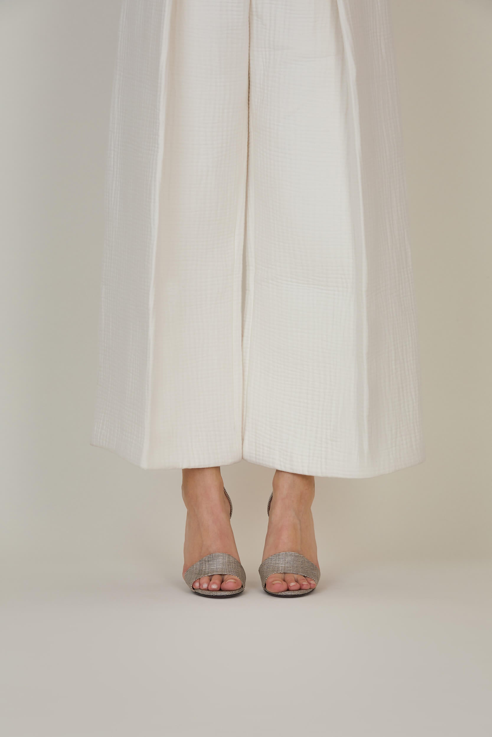 Sandale femme talon haut en lin enduit  – portée avec un pantalon blanc de chez Mazarine-Paris.  Une  Edition Signature de La Ligne Numérotée.