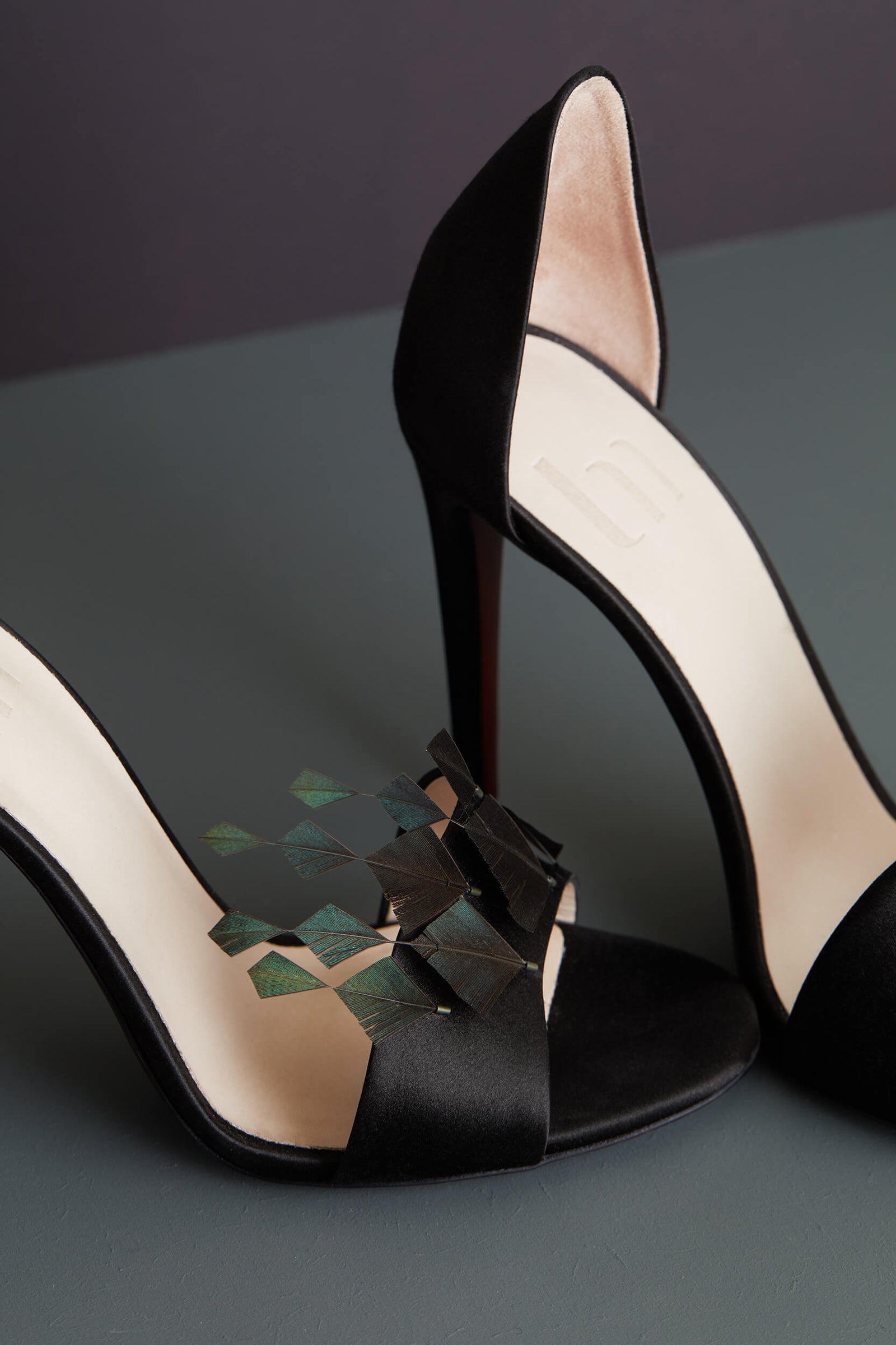 "L’Envolée" est une sandale haute en satin noir ornée de six plumes d’oie découpées, travaillées, sculptées puis brodées à la main. A la rencontre de l’Art et de la Couture, une Edition Limitée à Huit exemplaires. La Ligne Numérotée.